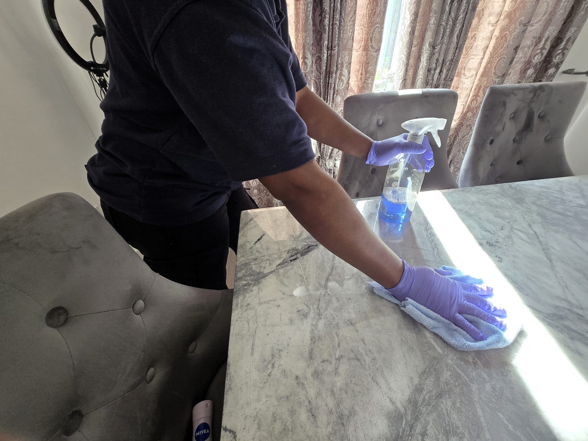 Zinomatt cleaner wiping a dining table during a residential cleaning service